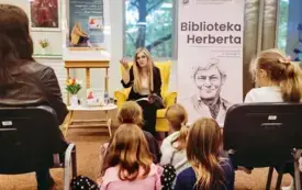 Autorka trzyma w rękach książkę i rozmawia z dziećmi o wartościach.
