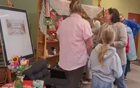 Autorka z uczestnikami wernisażu oglądają i omawiają szydełkowe wytwory.