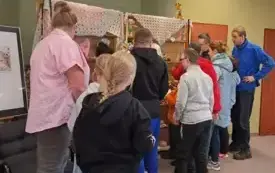 3.	Autorka z uczestnikami wernisażu oglądają i omawiają szydełkowe wytwory.