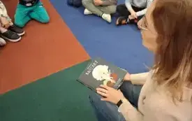 Bibliotekarka prowadzi pogadankę o muzyce. W rękach trzyma książkę z serii &bdquo;Mali Wielcy&rdquo; autorstwa Marii Isabel S&aacute;nchez Vegara &ndash; &bdquo;Mozart&rdquo;.