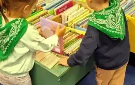 Dzieci wybierają książeczki z kolorowych kaseton&oacute;w.