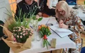 Kobieta i mężczyzna składają autografy.