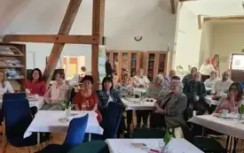 Uczestnicy spotkania siedzą przy stolikach.