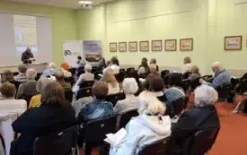Publiczność zgromadzona w sali. Z tyłu prof. Arkadiusz Kalin w trakcie przedstawiania kolejnego prelegenta