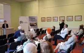 Publiczność zgromadzona w sali. Z tyłu po lewej stronie Rektor AJP Elżbieta Skorupska-Raczyńska wita zgromadzonych gości na tle plakatu konferencji