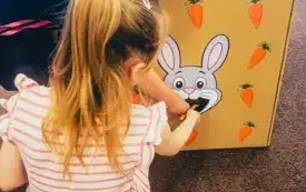 Dzieci karmią kartonowego kr&oacute;liczka marchewkami.