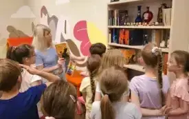 Bibliotekarka pokazuje dzieciom regał z książkami o Harrym Potterze
