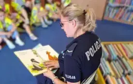 Nasz gość czyta dzieciom. Na plecach ma napis &bdquo;policja&rdquo;. Na obrazkach w książce znajdują się obrazki bohater&oacute;w opowieści &ndash; kruka i Mamy Mu.