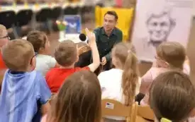 Patryk Małyszko prezentuje dzieciom profesjonalny mikrofon wykorzystywany w pracy radiowego dziennikarza.
