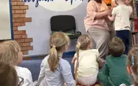 Dzieci przekazują kobiecie kwiaty w podziękowaniu