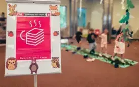 Plakat Dyskusyjnego Klubu Książki ozdobiony ilustracjami leśnych zwierząt. W tle dzieci.
