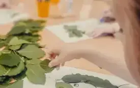 Dzieci tworzą portrety z wykorzystaniem liści.