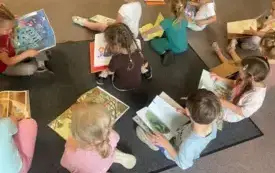 Dzieci siedzą na dywanie, przeglądają książki