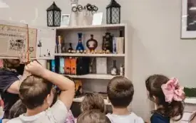 Bibliotekarka pokazuje uczniom książkę o Harrym Potterze.