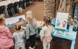 Bibliotekarka czyta dzieciom książkę &bdquo;Lato u babci&rdquo;.