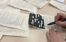 Stanowisko z blackout poetry - dłonie z flamasterm nad kartką ze starej książki