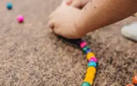 Dziecko nawleka koraliki do węża.