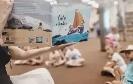 Bibliotekarka czyta dzieciom książkę &bdquo;Lato u babci&rdquo;.