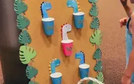 Dzieci biorą udział w zabawie &bdquo;koszyk&oacute;wka z dinozaurami&rdquo;, wrzucając piłki do koszyczk&oacute;w.