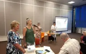Krystyna Kamińska oraz Edyta Plucińska stoją obok siebie przed publicznością i przemawiają do mikrofonu. W tle stoją Agnieszka Kopaczyńska-Moskaluk i Beata Igielska. 
