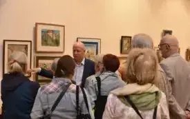 Klaudiusz Pohl oprowadza uczestnik&oacute;w wernisażu po wystawie, opowiadając o inspiracjach i miejscach przedstawionych na swoich akwarelach.