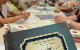 Na pierwszym planie okładka książki, na dalszym uczestnicy spotkania