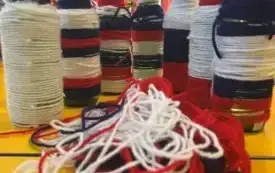 Szklane butelki ozdobione kolorową wł&oacute;czką ustawione na blacie