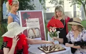 Panie siedzące przy stoliku, ubrane w stroje z lat ubiegłych.