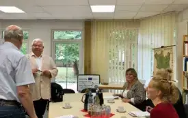 goście i gospodarze przy stole pogrążeni w rozmowie