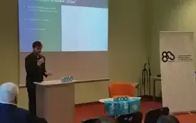 Zdjęcie przedstawia tę samą sytuację, tylko wykonano je w zbliżeniu na prelegenta i lekko z prawego profilu.