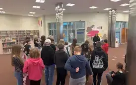 Bibliotekarka opowiada grupie dzieci o działalności Oddziału Dziecięcego.