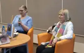 Agnieszka Kopaczyńska-Moskaluk oraz Joanna Ziembińska-Kurek siedzą na pomaranczowych fotelach, przed nimi stolik z wyeksponowanym tomikie poezji