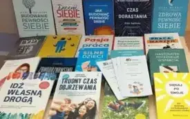 Wystawa książek prezentowana w Wypożyczalni Naukowej. Na stole znajdują się książki oraz ulotki informacyjne dotyczące konferencji i warsztat&oacute;w.  Publikacje są wyeksponowane w kilku rzędach, a obok nich umieszczono materiały promocyjne.