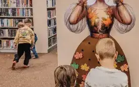 Dzieci ozdabiają sp&oacute;dnice Pani Jesień kolorowymi liśćmi.