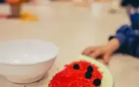 Dzieci wsypują ryż na poł&oacute;wki talerzyk&oacute;w.
