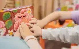 Dzieci dotykają wypukłych element&oacute;w w książce.