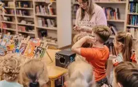 Przedszkolaki wyciągają losy i poszukują książki odpowiadającej opisowi.