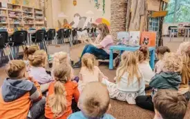 Bibliotekarka czyta dzieciom książkę w Oddziale Dziecięcym.
