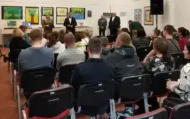 osoby siedzą na krzesłach, wnętrze biblioteki.