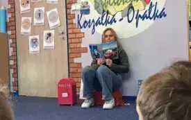 Kobieta pokazuje ilustracje z książeczki dzieciom.