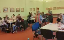 Wnętrze biblioteki. Uczestnicy "Moje literackie fascynacje" siedzą w ławkach.