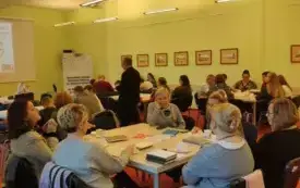 Wnętrze biblioteki. Uczestnicy "Moje literackie fascynacje" siedzą w ławkach.