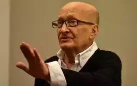 Wojciech Pszoniak unoszący dłoń w g&oacute;rę.