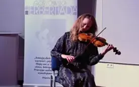 Artsytka gra na skrzypcach. Wnętrze biblioteki.