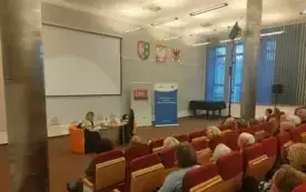 Spotkanie autorskie z Anną Kamińską. Publiczność słucha rozmowy dw&oacute;ch os&oacute;b na temat książki.