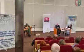 Dwie osoby siedzą na fotelach i rozmawiają na temat książki pt. "Putin car Atlantydy. Droga do wielkiej wojny". W tle publiczność.