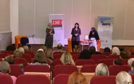 Publiczność siedzi na widowni. W tle autorka książki pt. "Chłopki. Opowieść o naszych babkach".