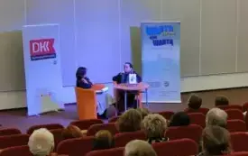 Publiczność siedzi na widowni. W tle autorka książki pt. "Chłopki. Opowieść o naszych babkach".