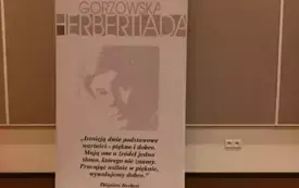 Baner "Gorzowskiej Herbertiady" umieszczony na podłodze. Obok znajdują się rysunki. Wnętrze biblioteki.