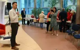 Grzegorz Urbanek przy mikrofonie, w tle autorzy i wydawcy zgromadzeni wok&oacute;ł stoisk